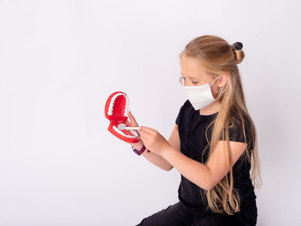 Meisje speelt tandarts met een gebitsmodel