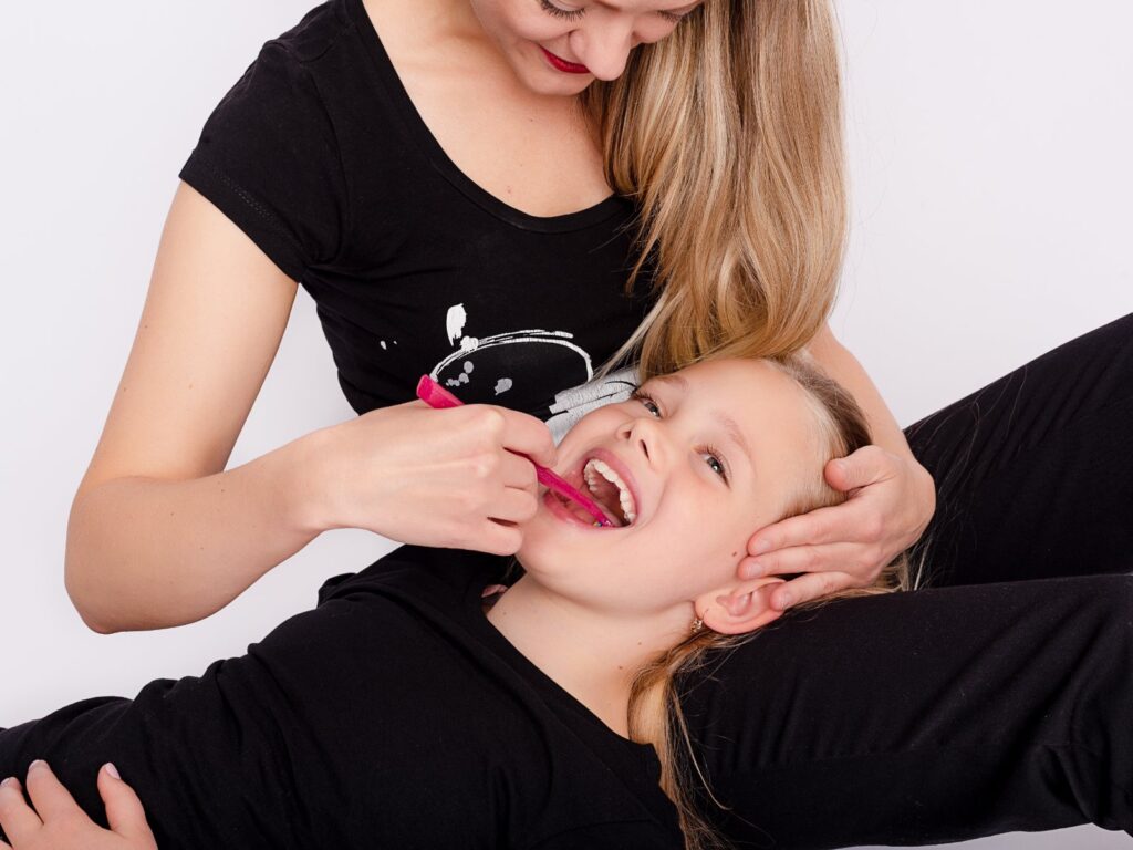 Mondhygiënist poetst de tanden van een lachend meisje